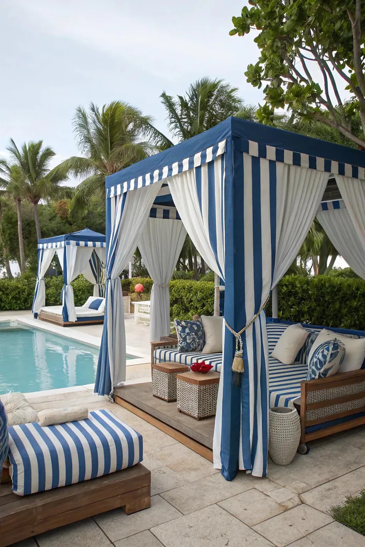 White and blue coastal-themed pool cabana with sheer curtains and nautical accents