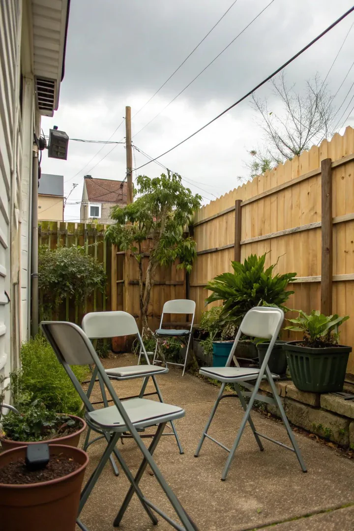 Folding bistro table and chairs set up on a small backyard paver patio